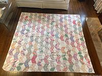 Top-down view of quilt laid flat on hardwood floor showing full tumbling block pattern and dimensions.