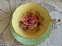 Top view of cup and saucer showing pink rose inside cup and mint green saucer with gold rim.