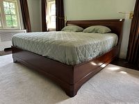 Front perspective showing low-profile footboard and side rails beneath a fitted mattress cover