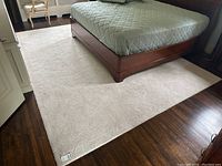 Full view of cream wool carpet under bed showing overall size and placement