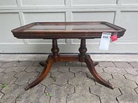 Full view of rectangular mahogany coffee table showing double pedestal base and brass capped claw feet.