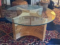 Top-down view showing round clear glass surface and X-shaped rattan support below