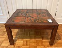 Front view of the mid century modern rosewood rectangular coffee table with tile inset on wood floor.