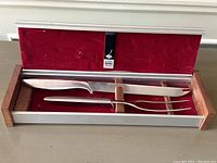 Full view of the Gerber stainless steel carving set in open original metal box with red velvet lining and wooden holders for two pieces.