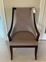 Front view of the armchair showcasing the dark wood frame and taupe upholstery, with a clear view of the high backrest and seat.