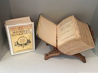 Both volumes side by side; reprint with dust jacket and original green-bound volume open on stand.