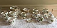 Full view of the Royal Albert White Dogwood tea set on a lace tablecloth showing multiple cups, saucers, small plates, creamer, and sugar bowl.