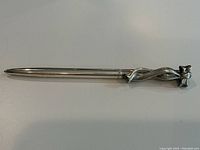 Full length image of the pen showing the slender silver body and the ribbon bow design at the top.