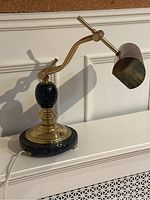Bankers table lamp showing marble base, brass elements, adjustable arm, and cylindrical shade from a front angle
