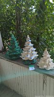 Full view of the three ceramic Christmas trees of different sizes and colors displayed side by side outdoors