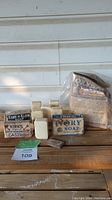 Multiple antique soap bars and boxed soaps displayed on wood surface, showing condition and variety of the lot.