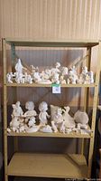Shelf with unpainted ceramic figurines and craft pieces shown, about 50 pieces total.