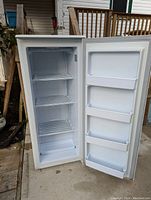 Interior of freezer with door open showing three wire shelves, bottom bin and molded door bins