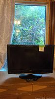 Full view of the RCA 31 inch TV placed on a wooden surface in front of a window.