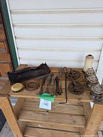 Photo of various vintage items on a wooden shelf including pulleys, glass insulators, metal springs, hooks, a strap pouch, and a large spool of twine.