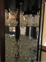 Wide shot showing multiple crystal vases and stemware glasses displayed in a cabinet