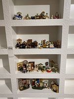 Four shelves filled with various miniature dollhouse furniture and accessories arranged neatly.