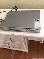Silver Accura DVD player with front tray and control buttons visible on front