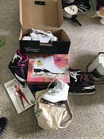 Overview of ice skates in different colors and sizes with the Pilates book and hand weights.