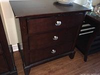 Full view of the wooden three drawer nightstand showing overall condition and design.