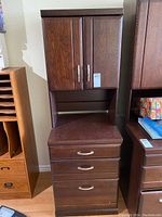 Front view of dark brown wood cabinet showing upper doors, open cubby, three drawers
