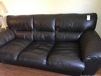 Full view of the black leather-like loveseat sofa showing three main seat cushions and padded arms.