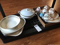 Overview photo showing 7 teacups, saucers stacked on trays, covered vegetable dish, Broil King platter and bowl, Royal Albert plate.