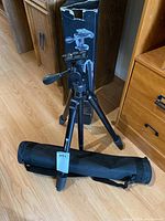 Platinum PT7956BG tripod fully extended with fluid pan head next to its original box and carrying case on wooden floor