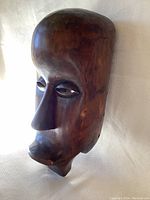 Front angle of the tribal mask showing elongated nose and smooth patina with slight surface wear.