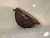 Side angled view of antique Ottoman military kettle drum showing animal skin lacing and drumhead.