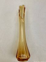 Front view of mid century light amber glass vase showing molded vertical ribs and scalloped rim.