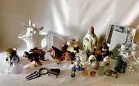 Assorted vintage knick knacks arranged on a draped cloth, showing variety of figurines, vases, glass bottles, and decorative pieces.