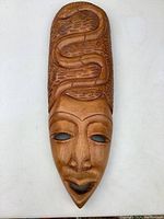 Full view of large wooden Tahitian mask showing face and serpent carving on forehead.