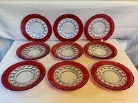 Set of nine ruby thumbprint luncheon plates arranged in rows showing front view with detailed borders