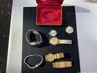 Group of six watches on black mat with red watch box lid