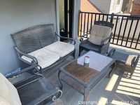 Patio furniture set including loveseat, two chairs, coffee table and end table on balcony with cushions