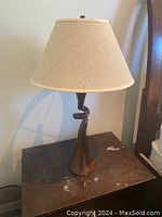 Single table lamp on side table showing twisted brown base and beige shade