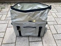 Front view of light grey waterproof floating knapsack with zipper pocket and black strap buckles