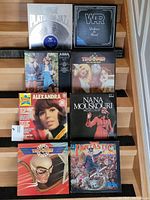 Photo showing 9 vinyl records arranged in three rows on wooden shelves. Visible records: WAR - Platinum Jazz, WAR - Deliver the Heat, ABBA - Greatest Hits, The Troggs (2 different albums), Alexandra, Nana Mouskouri, Fantastic.