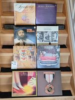 Vinyl records displayed on stairs showing the cover art of each album, including Demis Roussos, Electric Light Orchestra, Genesis, The Guess Who, and Sweet.