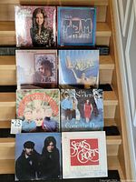 Eight vinyl records arranged on stairs, front covers visible including Mary MacGregor, Tim Weisner, The Seekers, Seals & Crofts, and others.