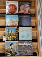 Eight vinyl records arranged on stairs showing album cover art and titles of various guitar and vocal music albums.