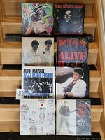 Front view of eight assorted vinyl records arranged in two groups, showing album cover art for Madonna, New Model Army, KISS, John Mayall, Michael Jackson, John Lennon, and Daniel Viglietti