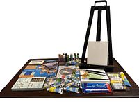 Overview photo showing all items spread on table including paints, brushes, canvases, embossing system, easel