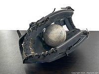 Black leather baseball glove with 'Dave Winfield' gold signature inside pocket and Cooper branding visible. Included white softball with surface wear visible inside glove pocket.