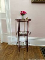 Full view of the three tier glass and metal stand showing all shelves and figurines.