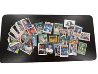 Large assortment of vintage baseball cards spread over a black surface, showing a mix of loose cards and some in sleeves.