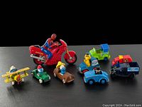 Overview photo showing the entire lot of vintage diecast toys including Smurf vehicle figures and Spiderman motorcycle.