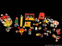 Overview of all assorted Playmobil playground equipment, figures, and ice cream set accessories laid out against black background.