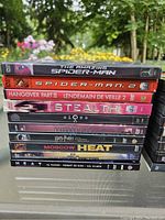 Stack of assorted DVDs showing titles including The Amazing Spider-Man, Spider-Man 2, Hangover Part II, Stealth, Harry Potter, Heat, Moscow Heat and others.